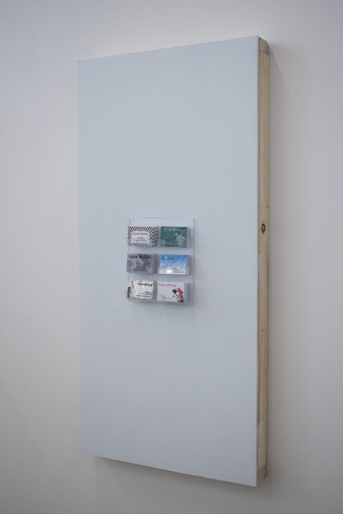 A light blue rectangle of painted plasterboard with a small rectangular plastic business card holder in the middle, mounted to a white wall.