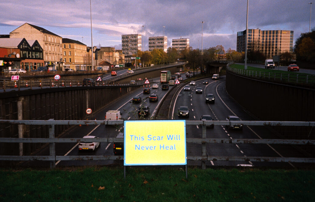Road sign reading 'this scar will never heal' on a motorway
